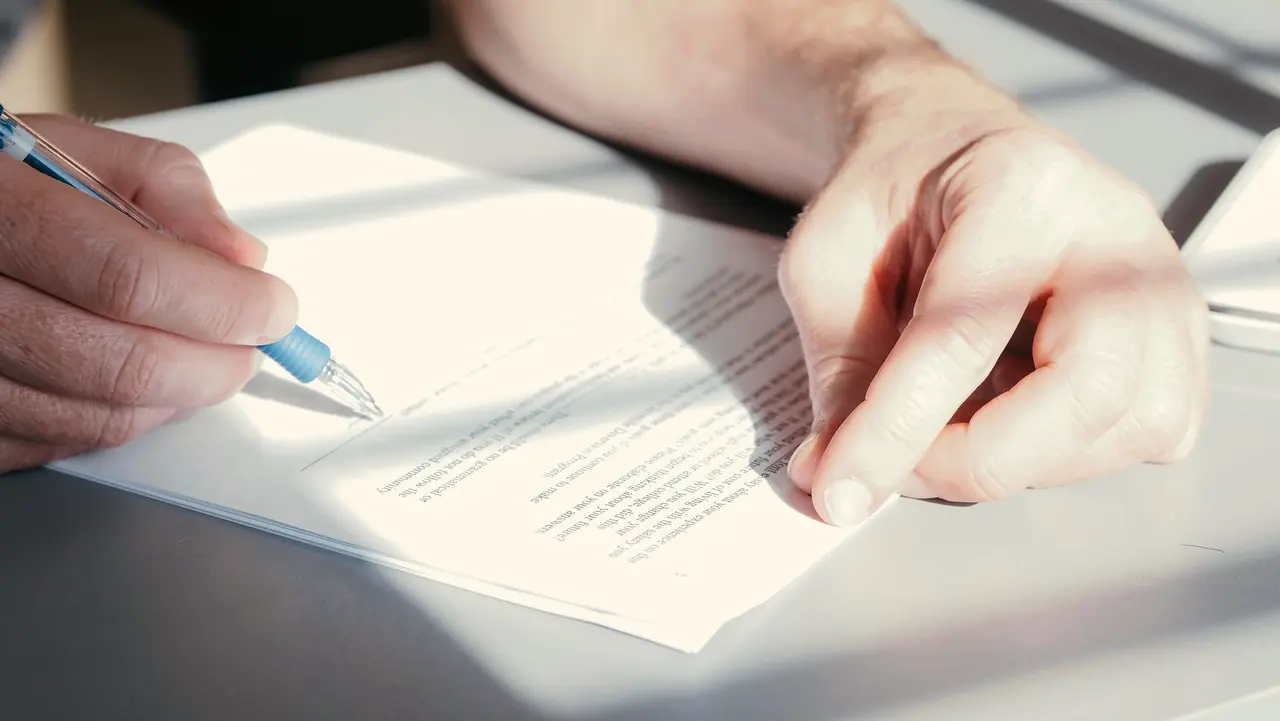 Hands signing a document